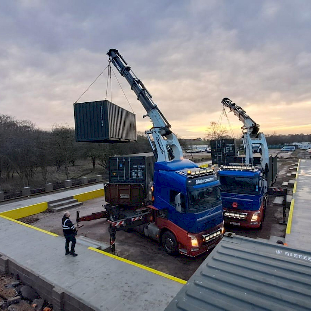 Shipping container being positioned on site using a crane